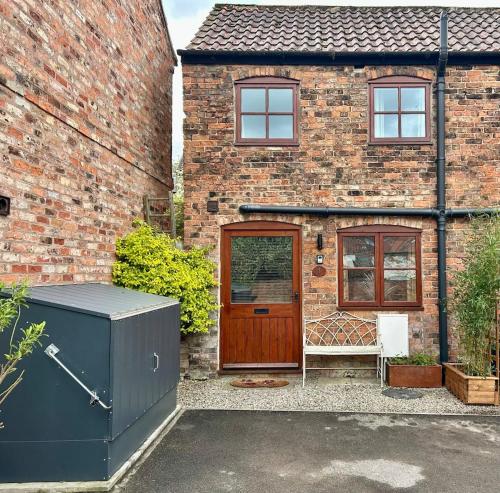 a brick house with a wooden door and a gate at 1 Bed cottage town centre free private parking cycle store Boroughbridge in Boroughbridge