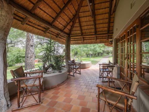 a porch with chairs and tables and trees at MILIMA Big 5 Safari Lodge in Hoedspruit