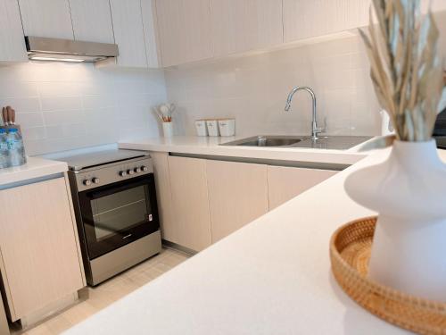 a white kitchen with a sink and a stove at Waters Edge 2 Bedroom Voyage in Yas Island