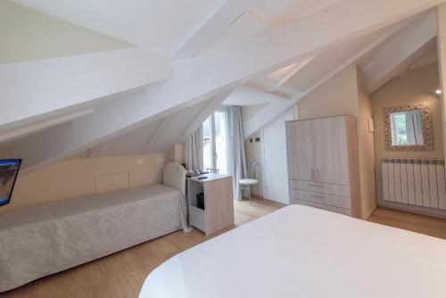 a white bedroom with a bed and a desk at Hotel Due Palme in Mergozzo