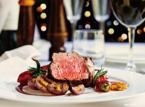 a plate of steak and potatoes on a table with a glass of wine at Kensington Hotel Yeouido in Seoul