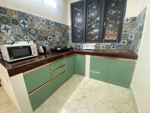 a kitchen with green cabinets and a microwave at Home away from home in Gangtok
