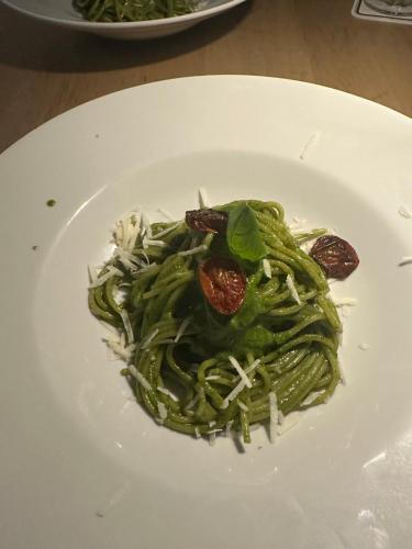 a white plate with green pasta on a table at Gasthof Neusitz in Neusitz