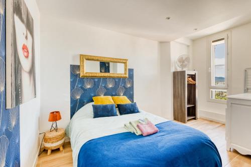 une chambre avec un lit avec des oreillers bleus et jaunes dans l'établissement T2 -Le Winter Palace, Vue Mer, à Saint-Raphaël
