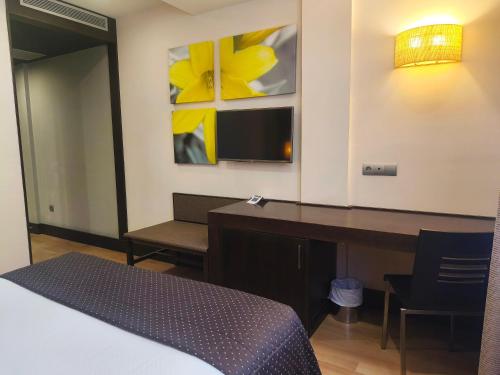 a hotel room with a desk and a bed at Hotel Sercotel Cuatro Postes in Avila
