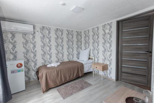 a small bedroom with a bed and a refrigerator at Перлина Карпат in Pistyn