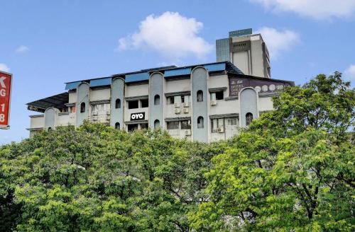 a tall building with trees in front of it at Super Hotel O Golden Suites in Turambhe