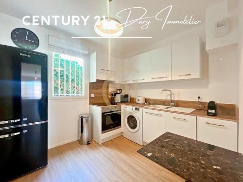 une cuisine avec des armoires blanches et un réfrigérateur noir dans l'établissement Calvi T3 Les Jasmins proche centre, à Calvi