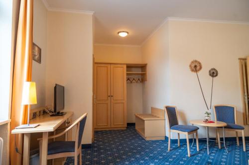 a hotel room with a desk and chairs and a room at Bischofshof Braustuben in Regensburg