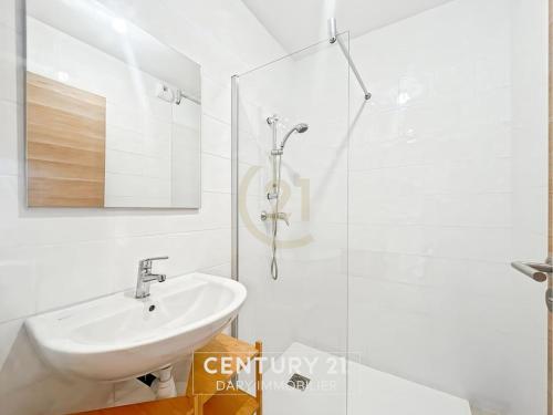 une salle de bain blanche avec un lavabo et une douche dans l'établissement Calvi T2 les Jasmins proche centre, à Calvi