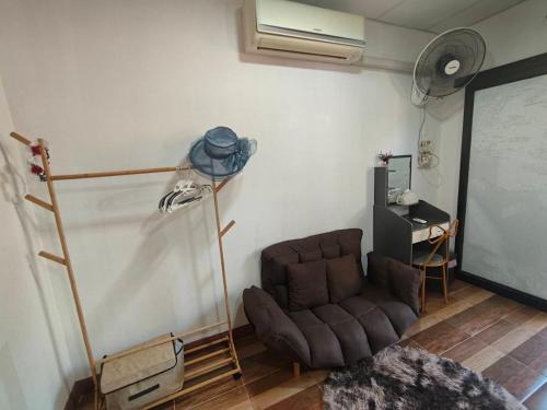 a living room with a brown chair and a table at Maidok Homestay(ไม้ดอกโฮมสเตย์) in Ban Pak Ba Ra