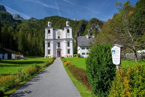 ein großes weißes Haus mit einer Straße davor in der Unterkunft Gasthof Maria Kirchental in Sankt Martin bei Lofer