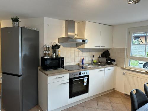 a kitchen with a stainless steel refrigerator and white cabinets at Gästehaus am Bach in Rust