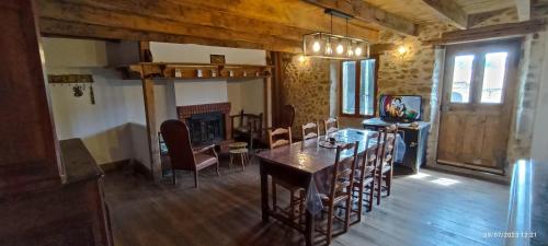 une salle à manger avec une table et des chaises et une cheminée dans l'établissement Gite rural aux portes de l'Auvergne, à Les Serres