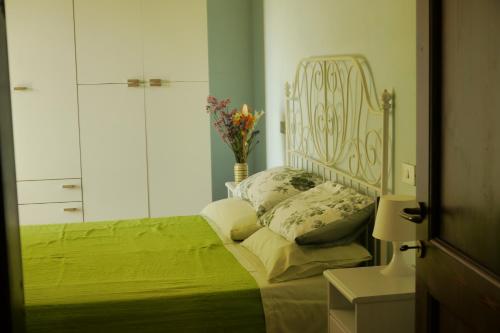 Un dormitorio con una cama verde y un jarrón de flores en agriturismo La Giana, en Valfabbrica