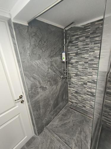 a shower with a glass door and a stone wall at Family&Friends in Ceahlău