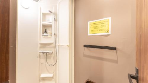a bathroom with a toilet with a sign on the wall at Tabist MAYUDAMA CABIN in Yokohama