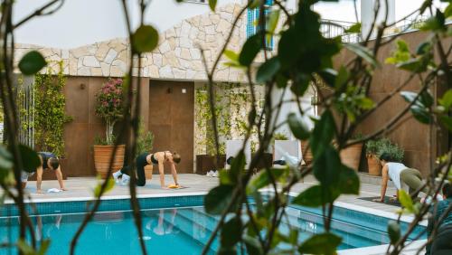 a group of people doing yoga by a swimming pool at LIV & CO Suites & Villas in Voroklini