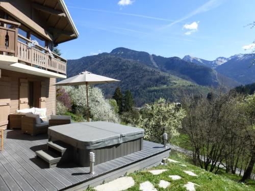 a patio with a table and an umbrella and mountains at Chalet Serein in Seytroux