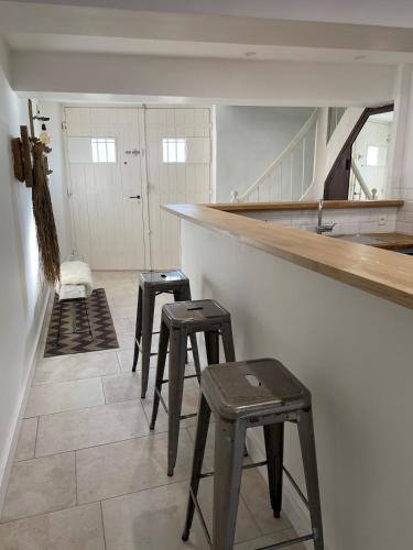 une cuisine avec trois tabourets et un comptoir avec des escaliers dans l'établissement Le Petit Camisou, un écrin au pied de la Cité, à Carcassonne