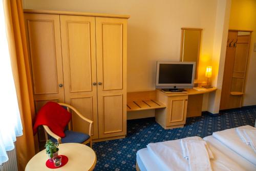 a hotel room with a bed and a television at Bischofshof Braustuben in Regensburg