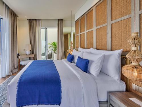 a bedroom with a large bed with blue and white pillows at Royal Avila Boutique Resort in Senggigi 