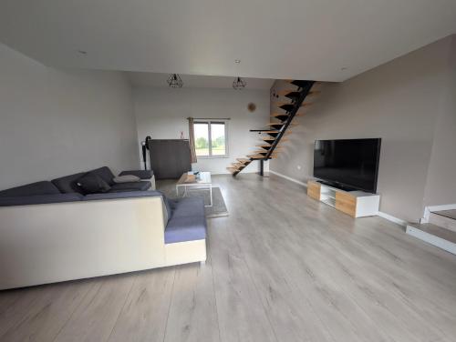 a living room with a white couch and a television at Nid paisible avec un coin terrasse in Faramans