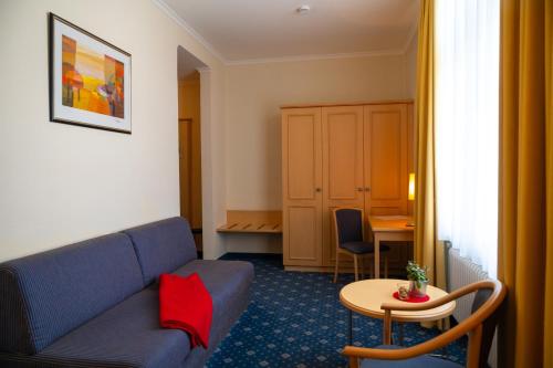 a living room with a blue couch and a table at Bischofshof Braustuben in Regensburg
