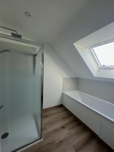 une salle de bain avec un puits de lumière et une douche en verre dans l'établissement Gîte de la Rosaline, à Saint-Jacques-de-Néhou