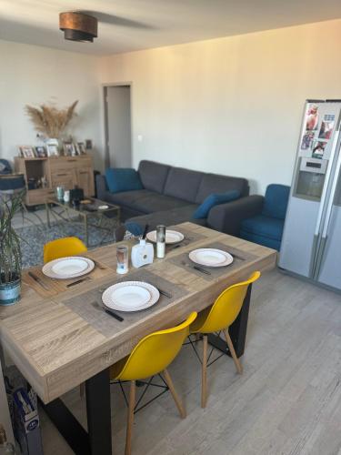 - une table en bois dans le salon avec des chaises jaunes dans l'établissement Beautiful appartement near 24h du Mans !!!, au Mans
