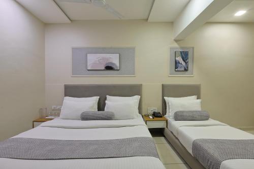 two beds in a room with white walls at HOTEL SHALIGRAM in Ahmedabad