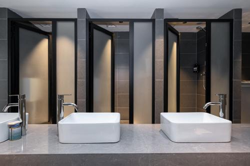 two sinks in a bathroom with two mirrors at 际庭青年旅舍-马当路地铁站店 in Shanghai