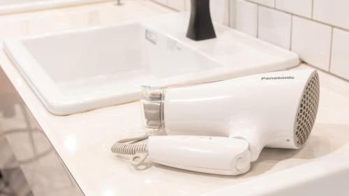 a hair dryer sitting on a bathroom sink at Tabist MAYUDAMA CABIN in Yokohama