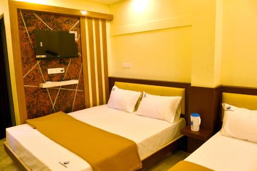 a hotel room with two beds and a television at Dhivyam residency in Palani