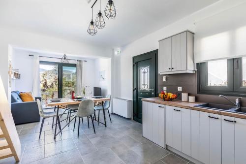 a kitchen with white cabinets and a table with chairs at Marani Home & Villas in Skopelos Town