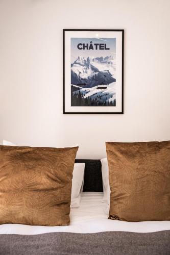 a bed with two pillows and a picture on the wall at Apartment Montami, Châtel - by EMERALD STAY in Châtel