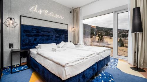 a bedroom with a large bed with a large window at Aparthotel Biała Perła - Czarna Góra Resort, Sun & Snow in Sienna