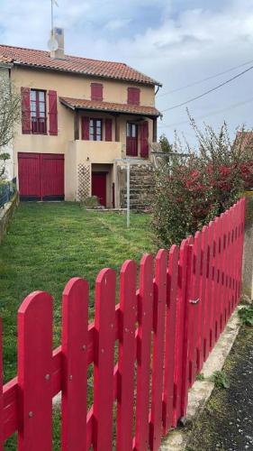 une clôture rouge devant une maison dans l'établissement Maison de campagne chaleureuse, à Léotoing