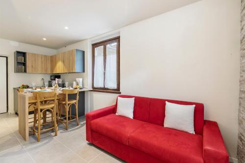 a red couch in a living room with a kitchen at Appartamento 30 NODI Torbole - Happy Rentals in Nago-Torbole