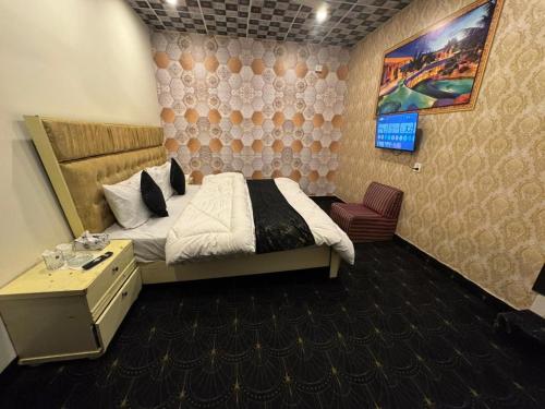 a bedroom with a bed and a tv in it at Hotel Hayat Palace Johar Town in Lahore