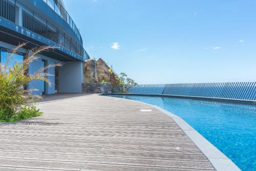 a wooden walkway next to a building with a swimming pool at Mar Apartment by Atlantic Holiday in Câmara de Lobos