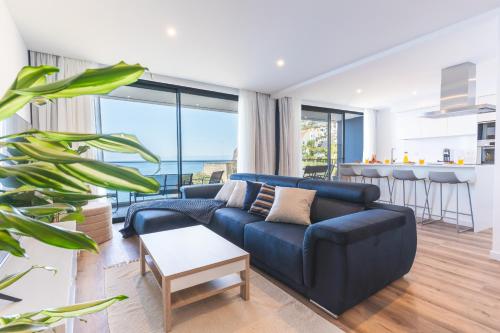 a living room with a blue couch and a table at Mar Apartment by Atlantic Holiday in Câmara de Lobos