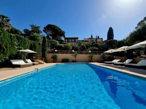 une grande piscine bleue avec chaises et parasols dans l'établissement Villa 4 étoiles - parking - wifi - clim - piscine, à Sainte-Maxime