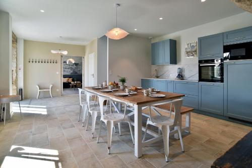 une cuisine avec des armoires bleues et une table et des chaises dans l'établissement Esprit Famille - Grand Jardin, à Dinan