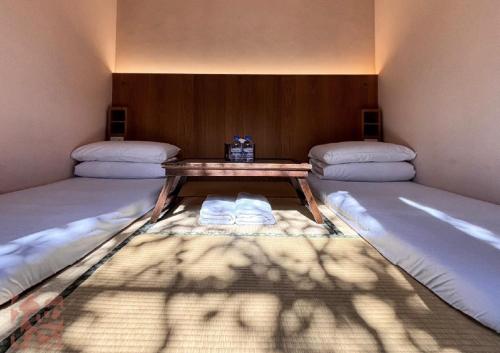 a room with two beds and a wooden table at 德旅店 Dehostel in Pingtung City