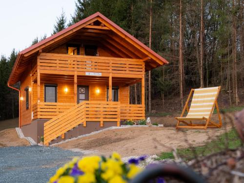 a wooden cabin with a chair in front of it at Era's Home Apartman in Apátistvánfalva
