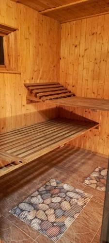 a wooden sauna with two bunk beds and a rug at Domek rustykalny z sauną nad samym jeziorem in Leleszki
