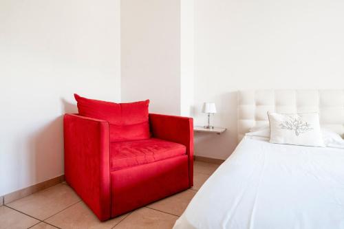 a red chair in a bedroom next to a bed at Case Vacanze Otranto in Otranto