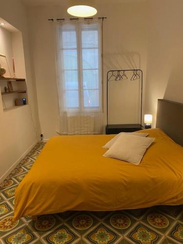 - une chambre avec un grand lit jaune et une fenêtre dans l'établissement Les Salines de la Roquette, à Arles