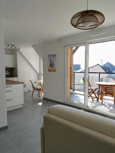 Il comprend un salon avec un canapé et une cuisine avec un balcon. dans l'établissement Appartement neuf, calme et ensoleillé, à Cabourg
